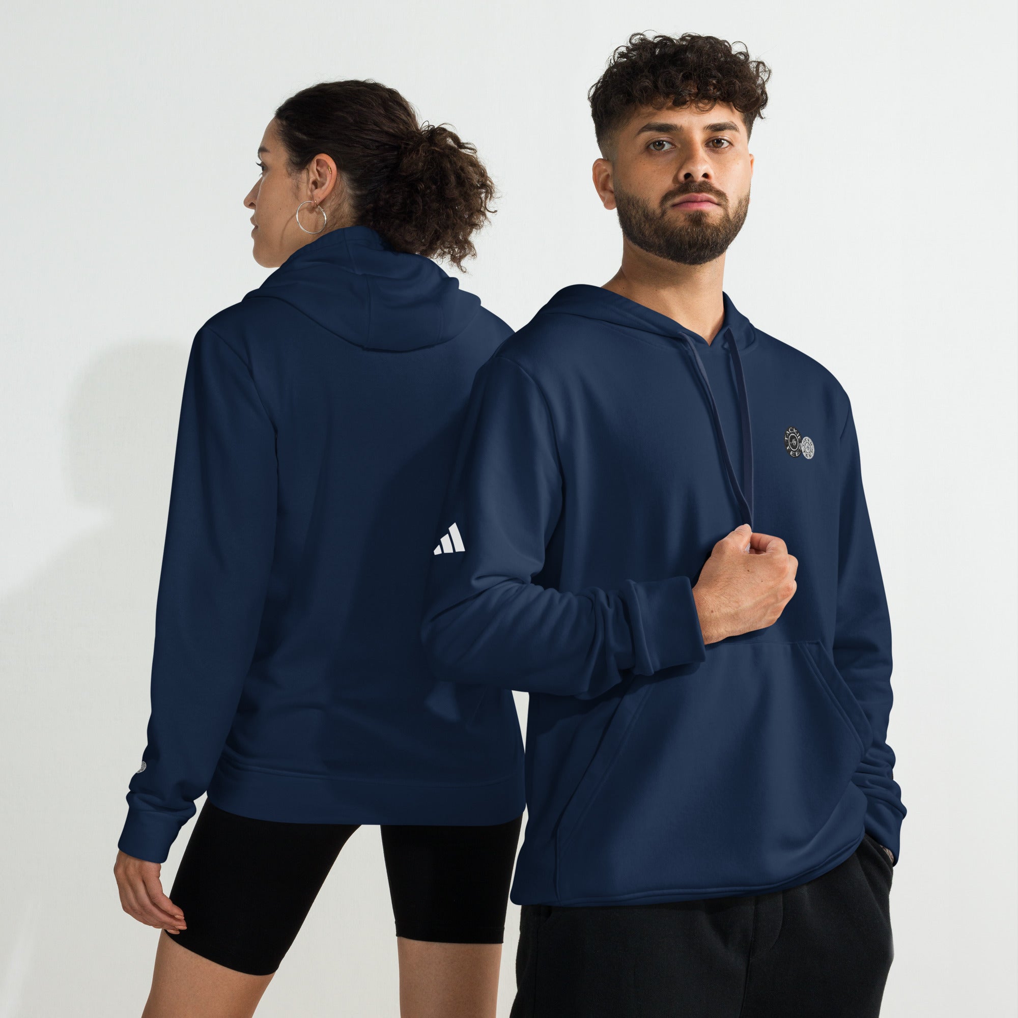 Man and woman wearing navy Adidas x Signature embroidered fleece hoodies, showcasing front and back views.