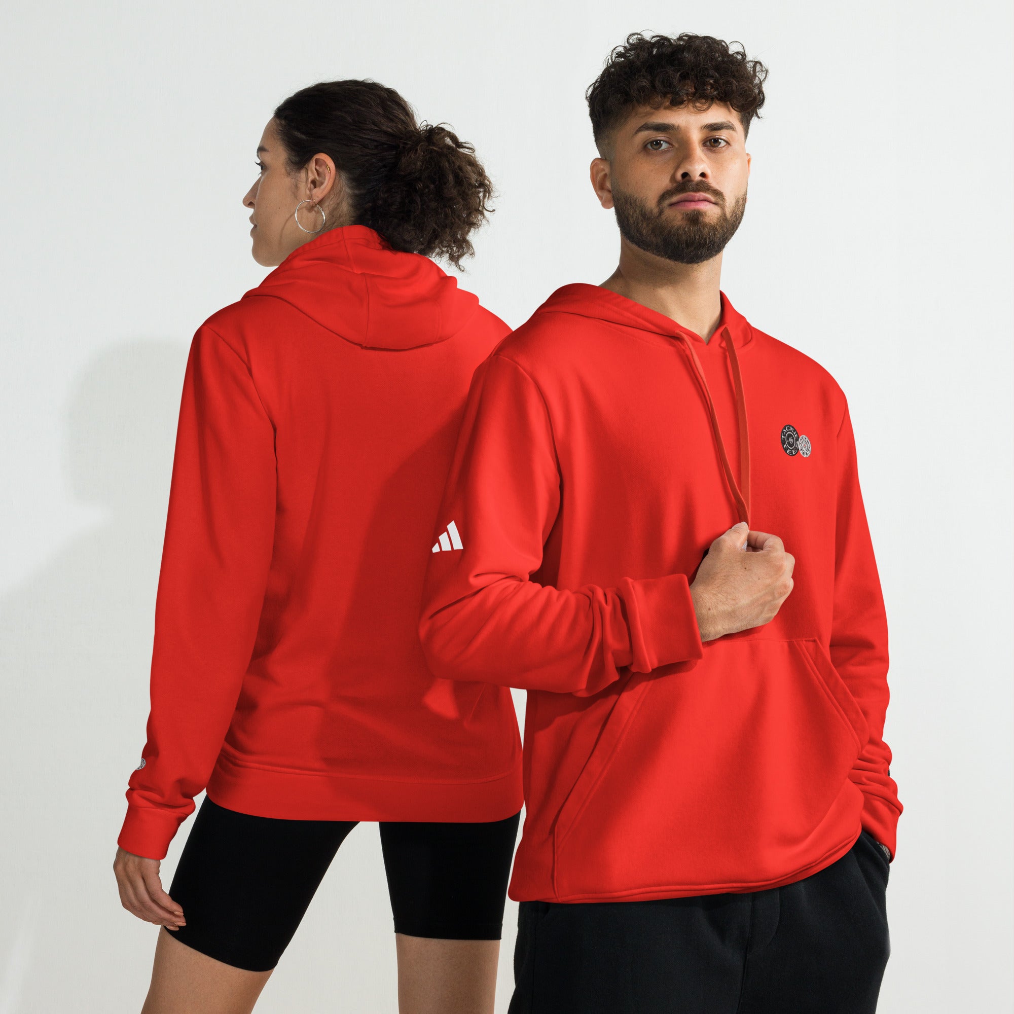 Two people wearing red adidas x Signature embroidered fleece hoodies, showcasing front and back views.